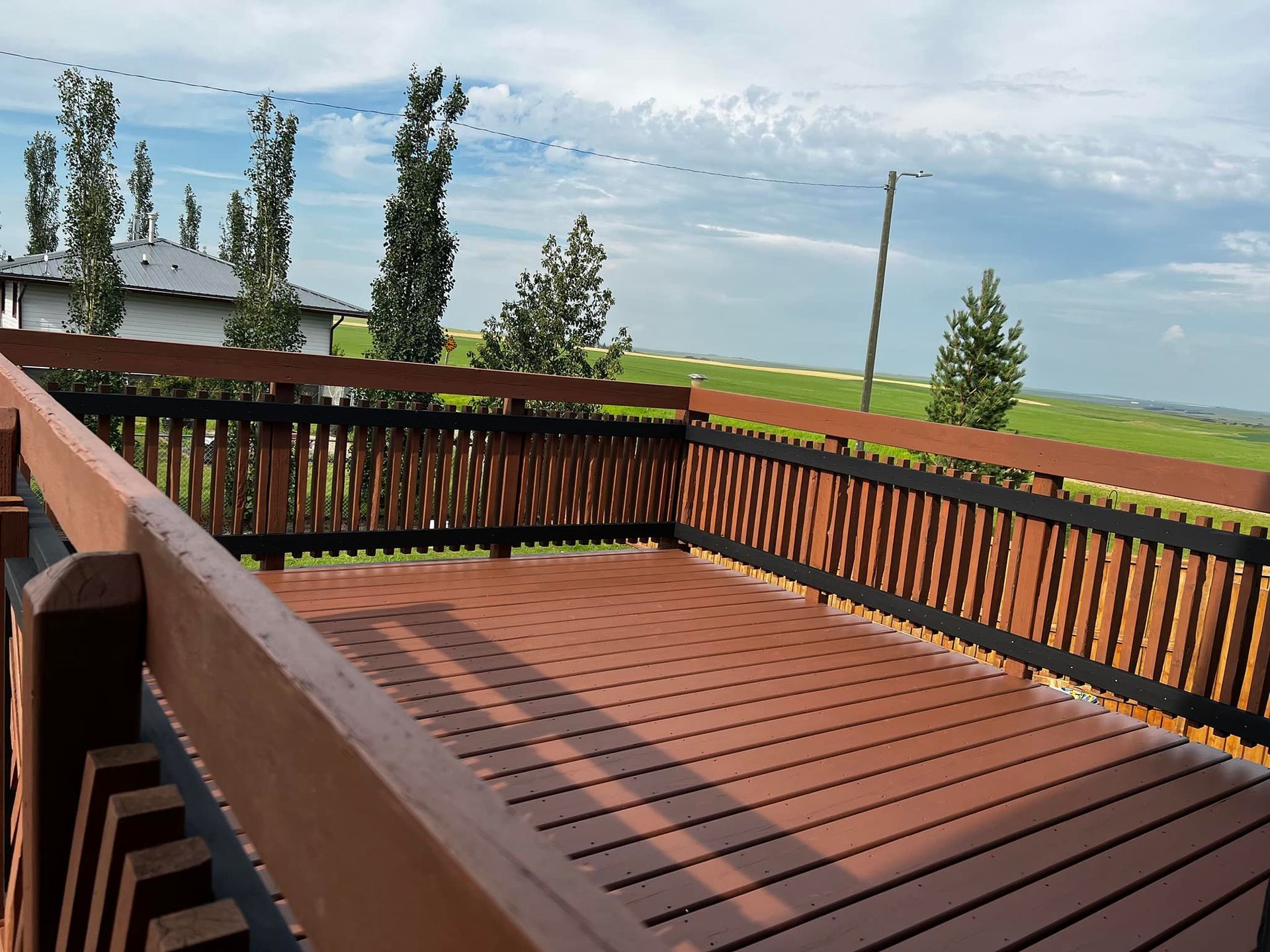 A wooden deck with a fence and a view of a field
