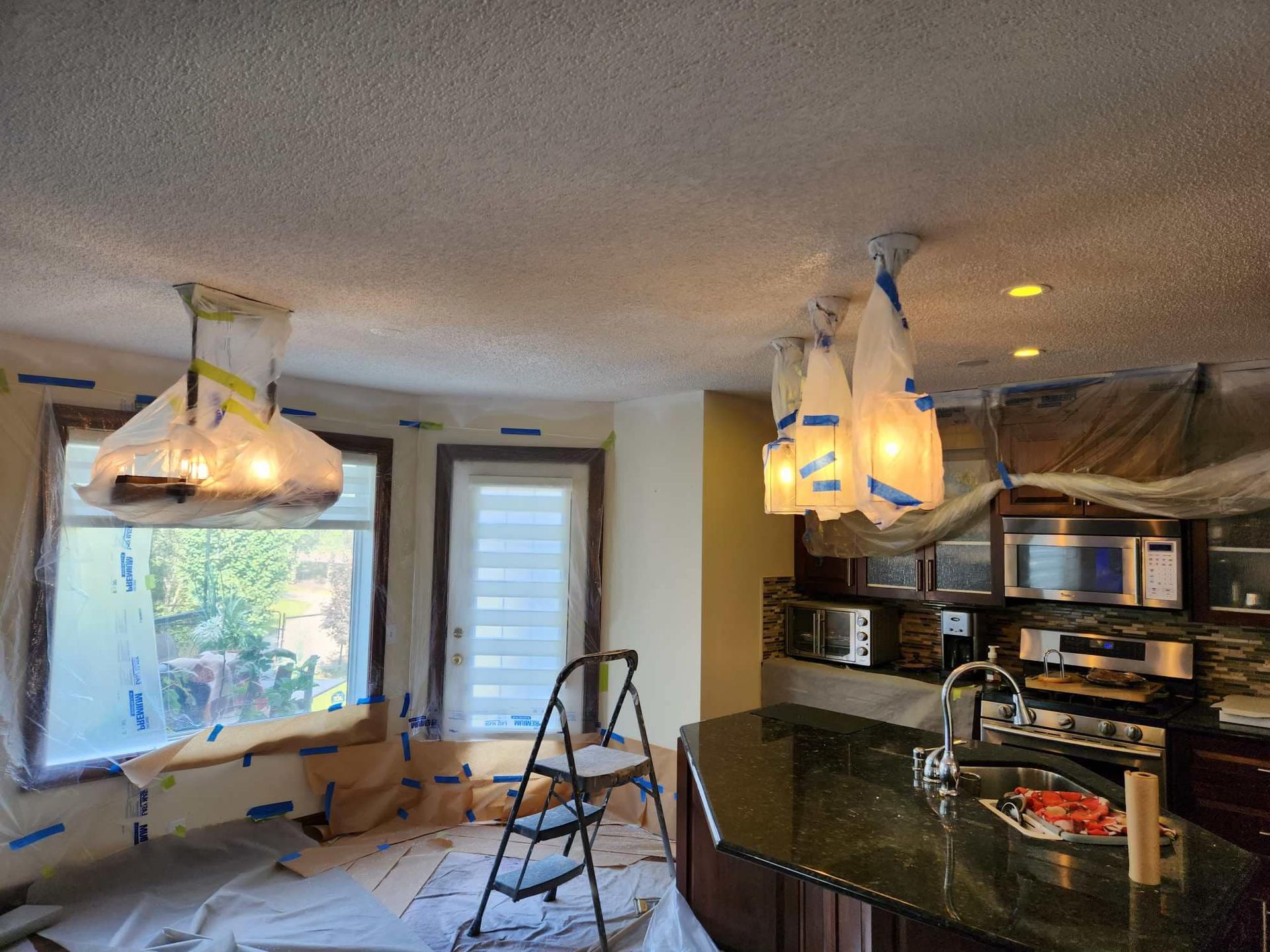 A kitchen is being painted with a ladder in the foreground.