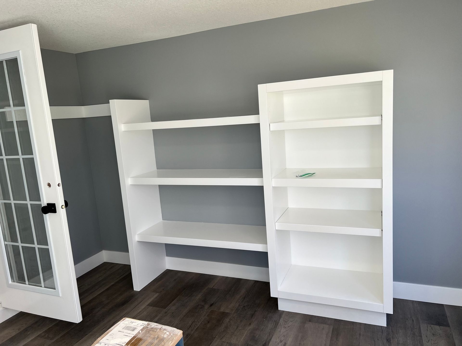 A living room with two white shelves and a french door