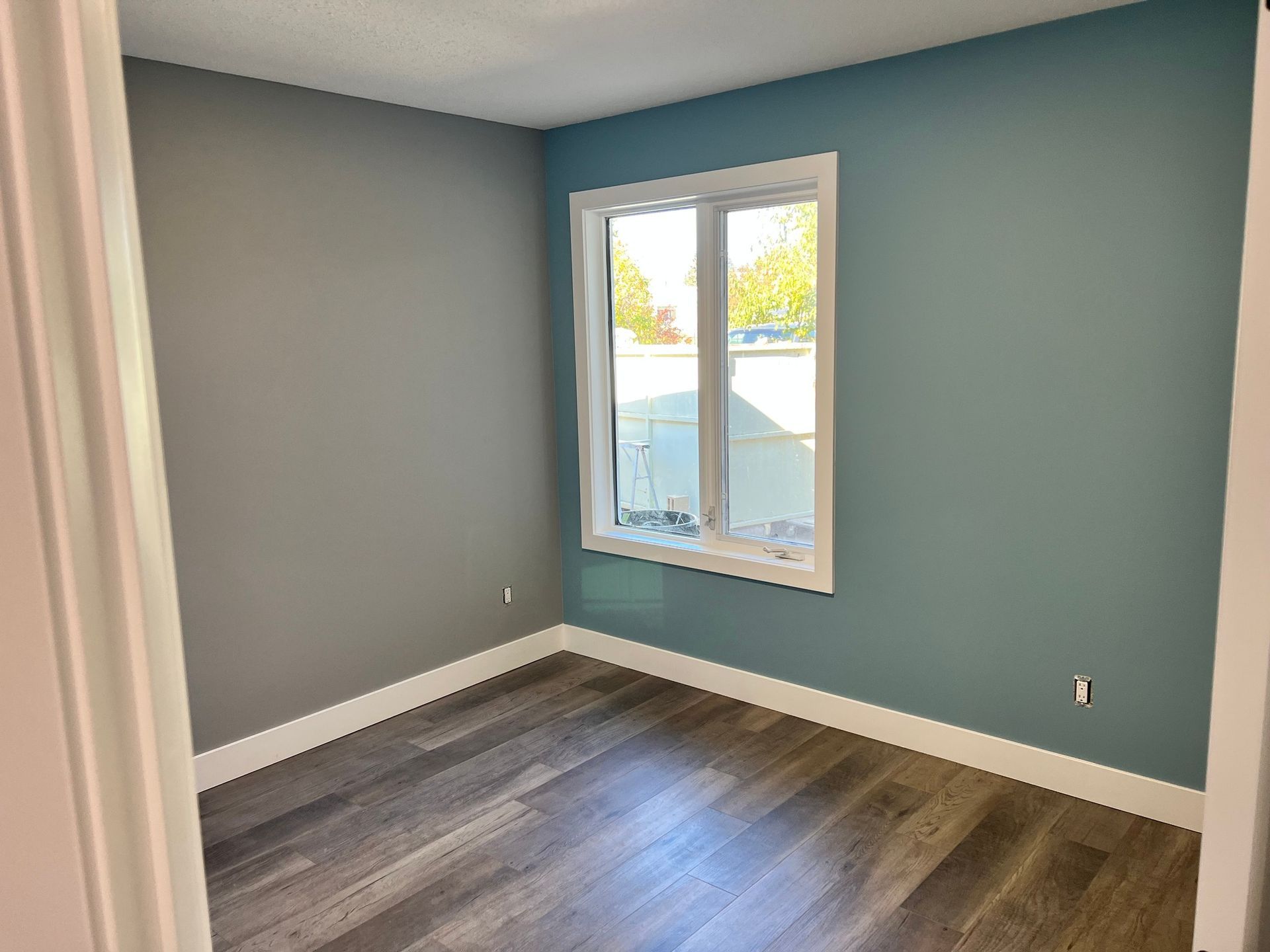 An empty room with blue walls and a window.
