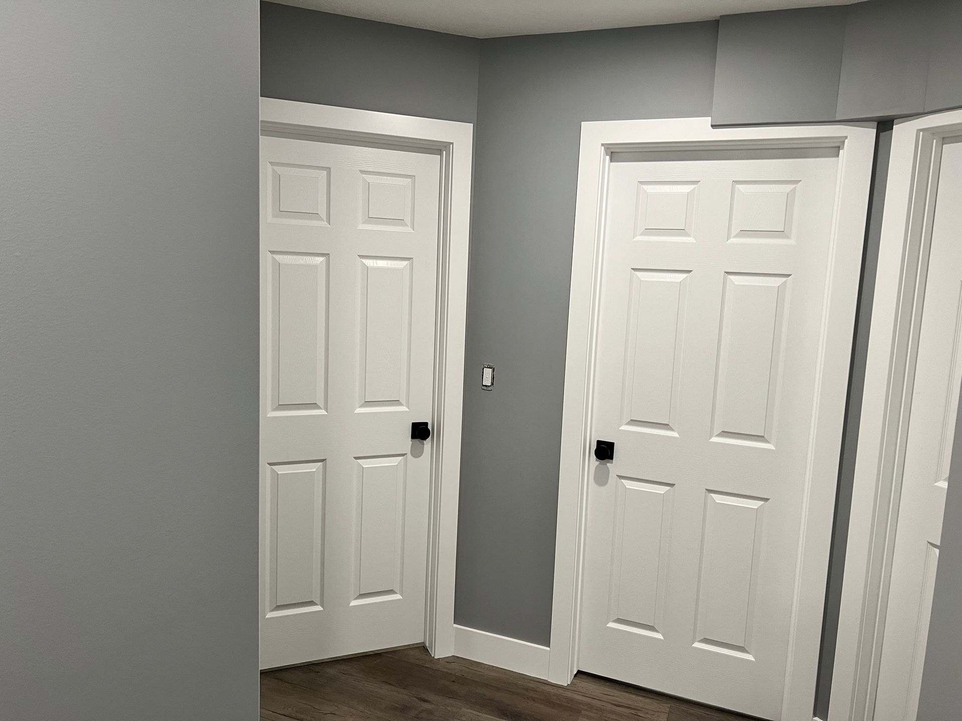 A hallway with two white doors and gray walls.