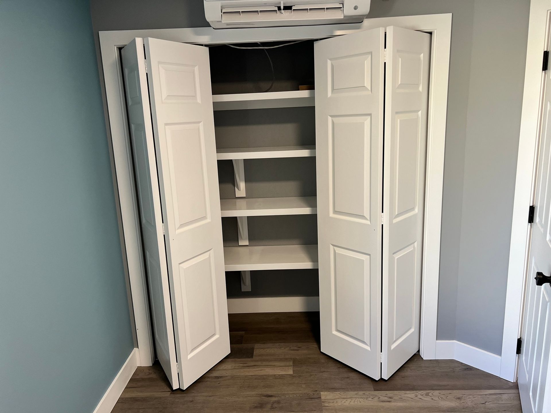 A closet with shelves and folding doors in a room.