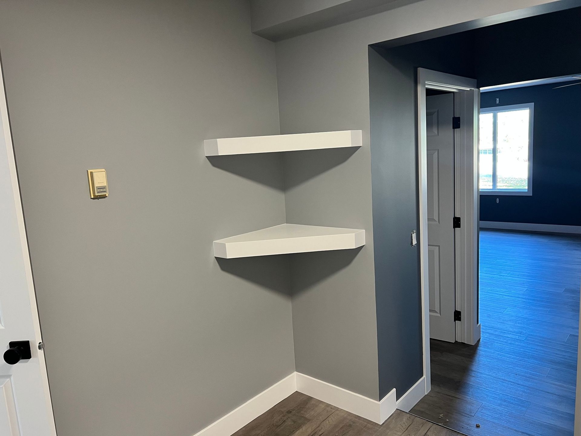There are three shelves in the corner of the room.