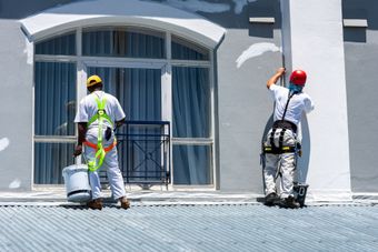Two men are painting the side of a building.
