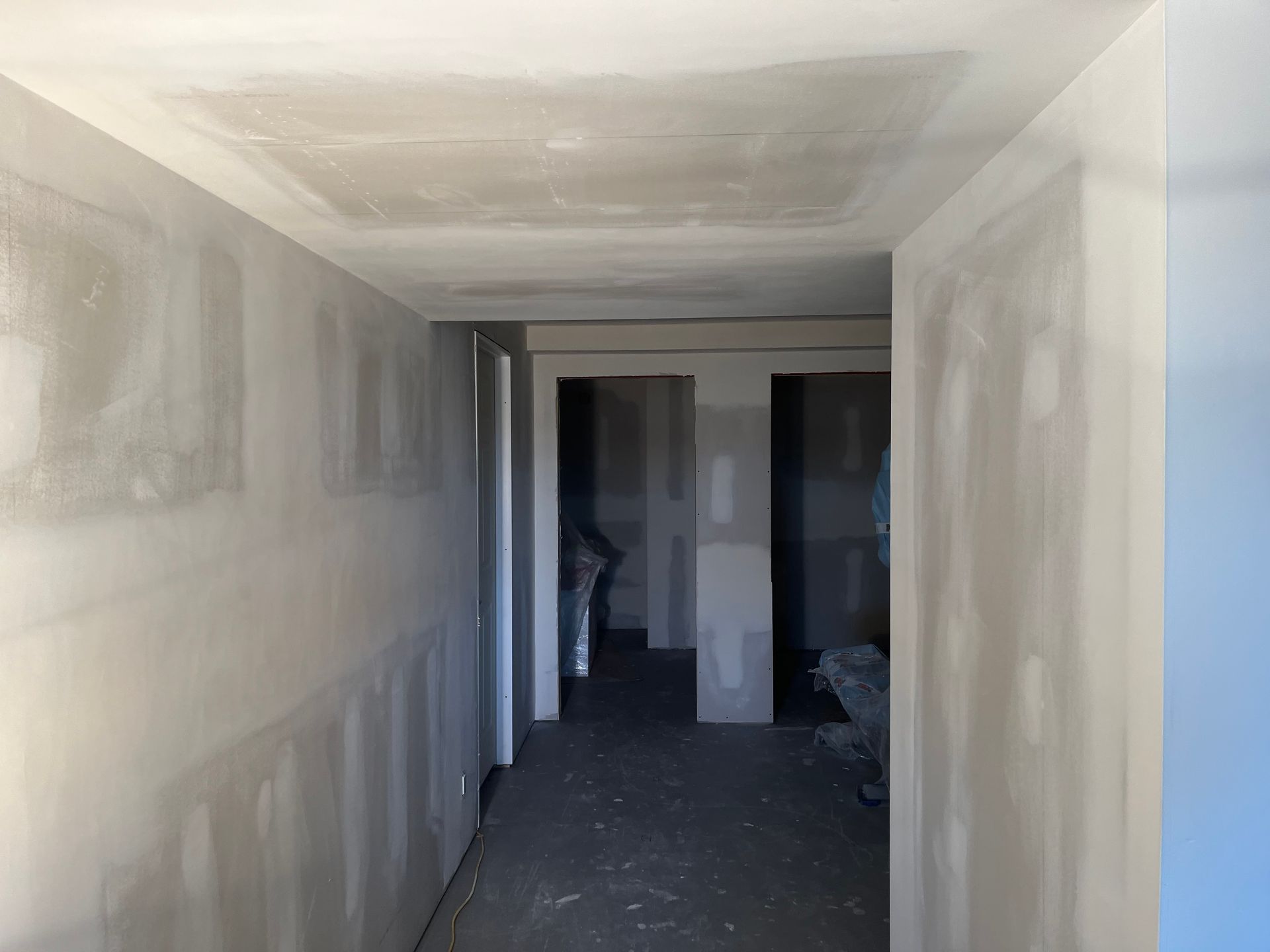 A hallway with drywall walls and a ceiling in a building under construction.