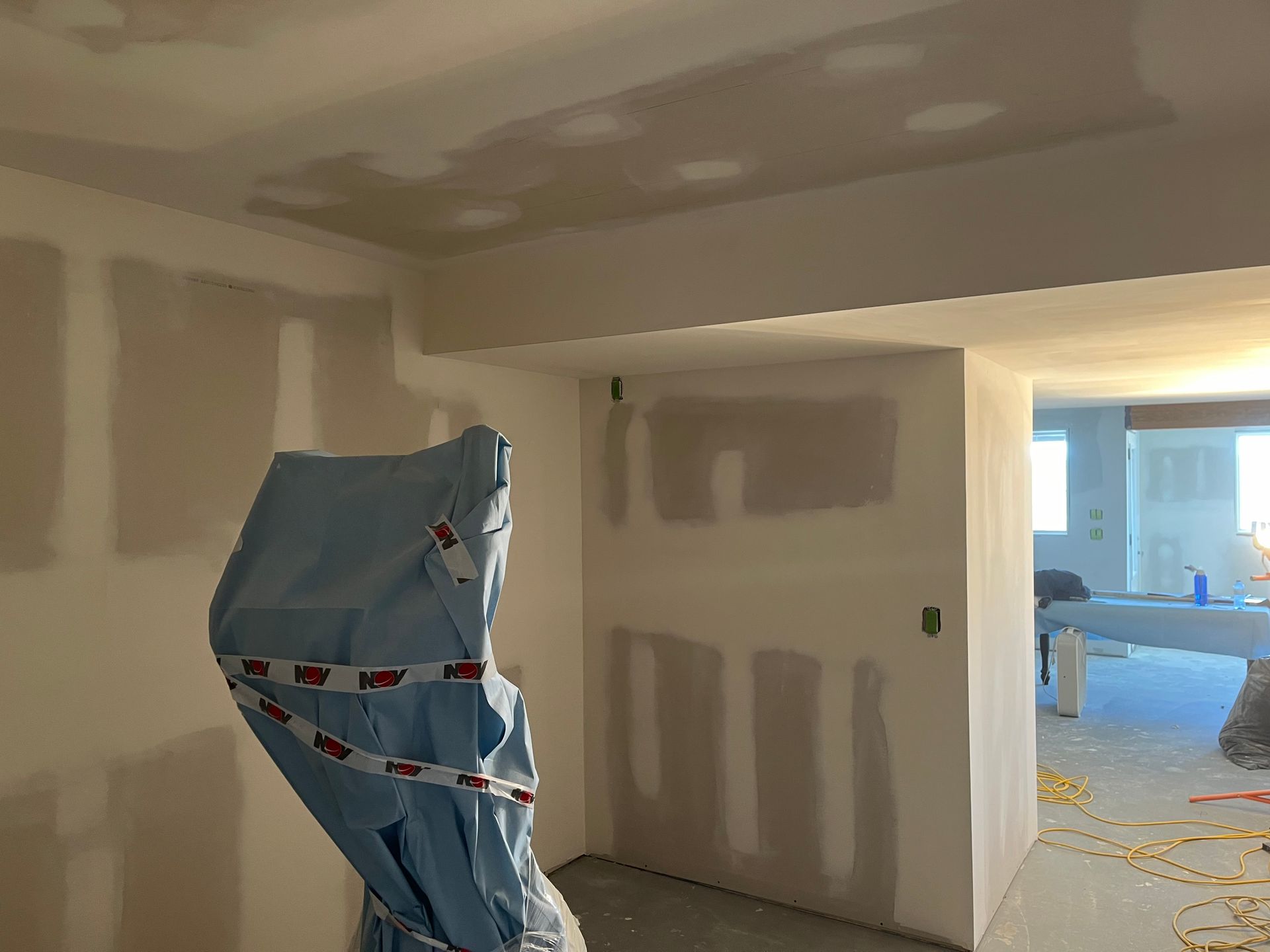 A room with white walls and a blue tarp on the floor.