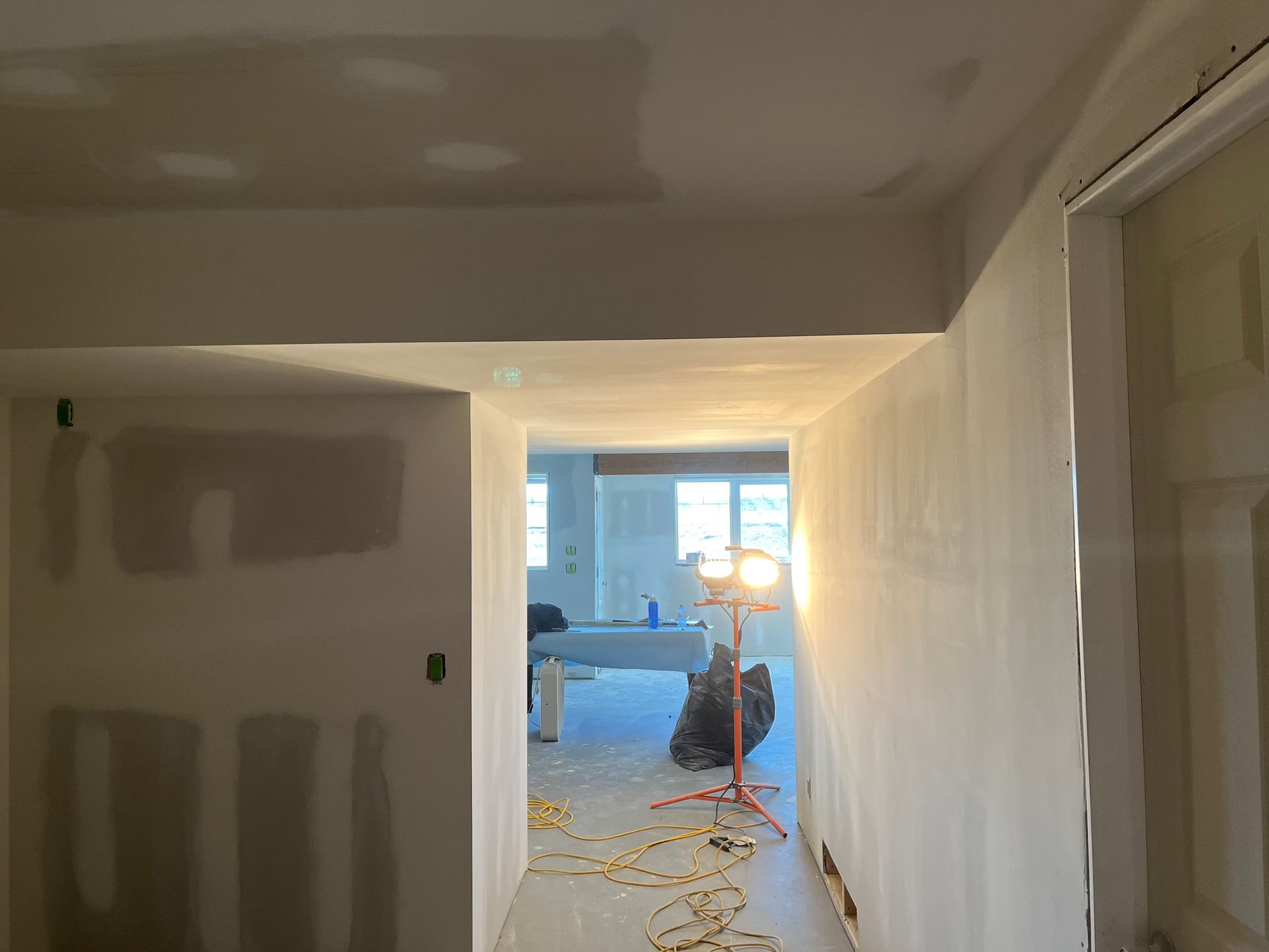 A hallway with drywall walls and a light on the floor.