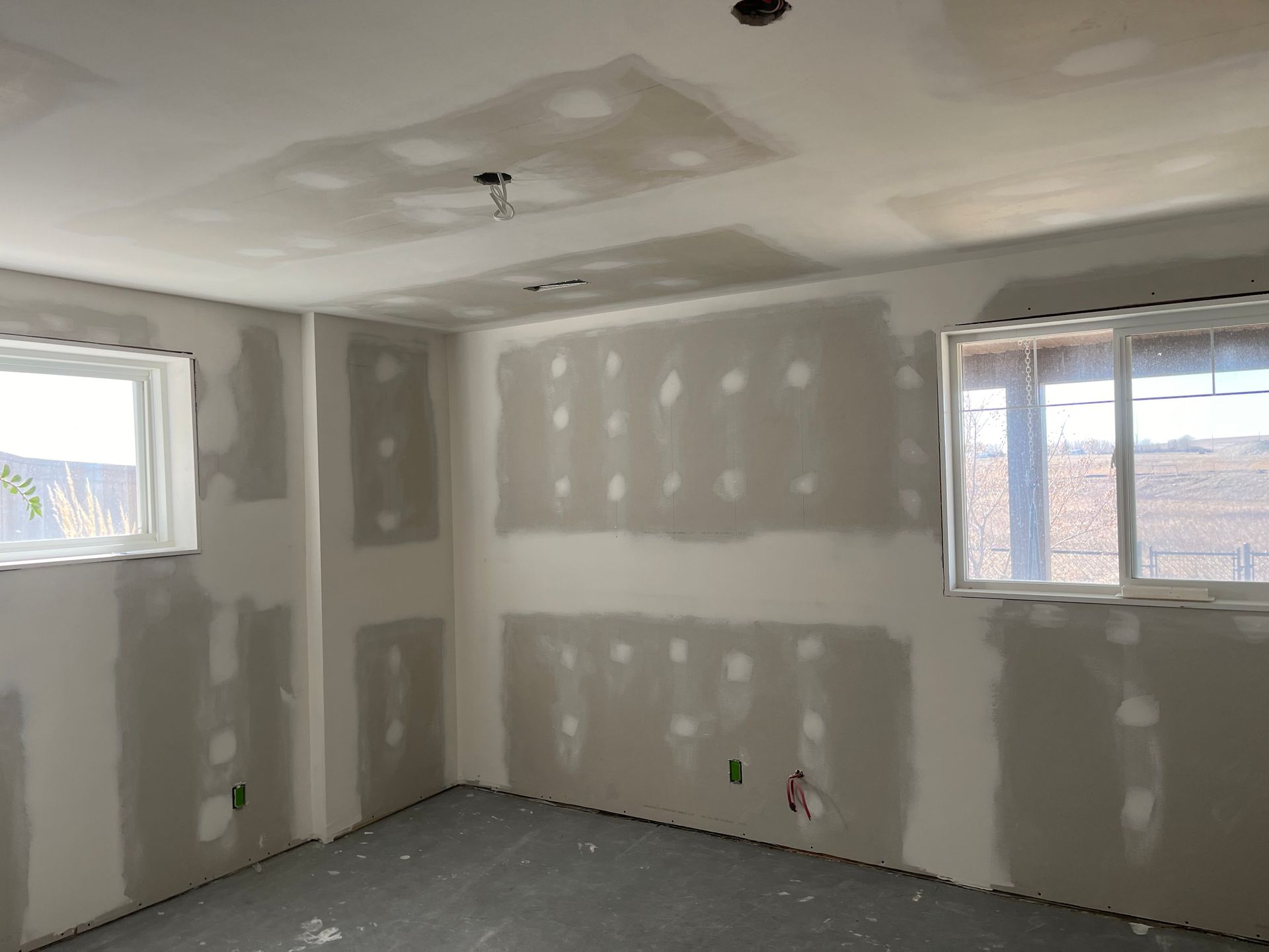 A room with a lot of drywall on the walls and a window.