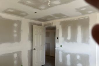 A room with drywall on the walls and a door.