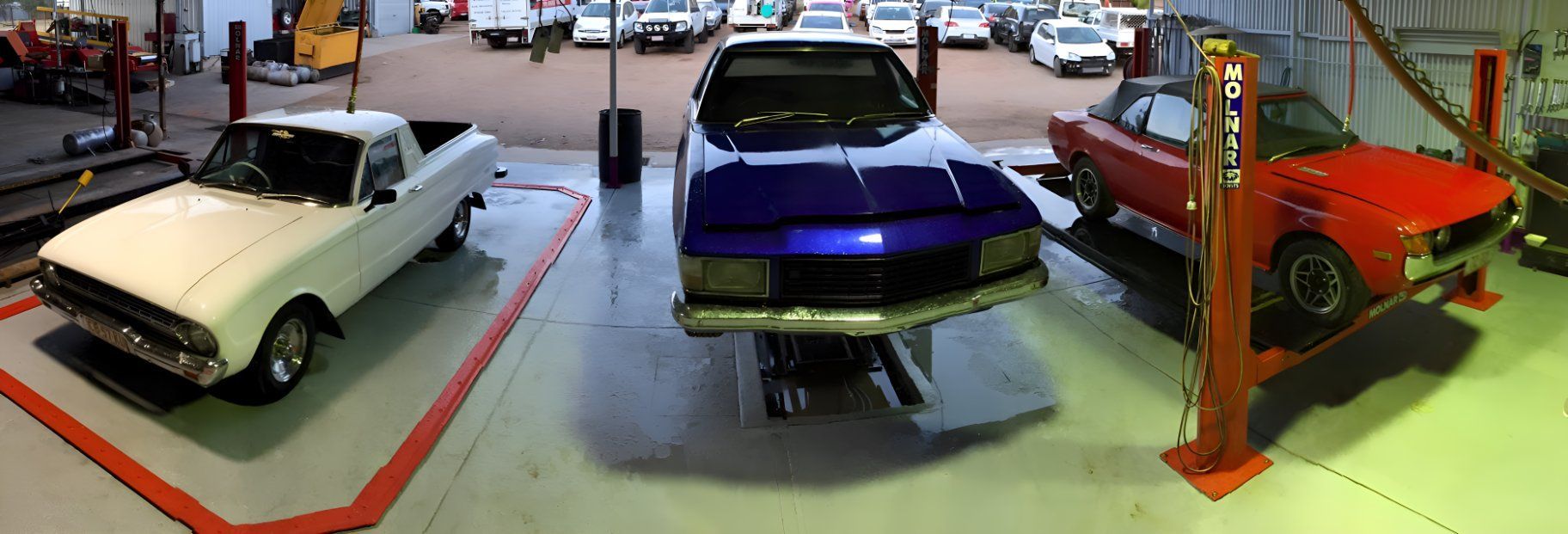 A White Truck , A Blue Car And A Red Car Are Parked In A Garage — P & V Panel Works In Alice Springs, NT