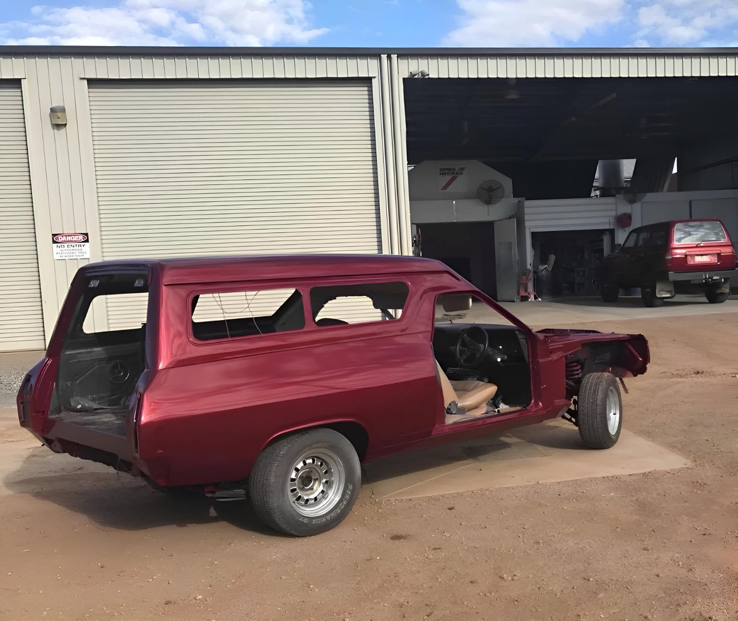A Red Car Is Parked In Front Of A Garage With The Number 7 On It — P & V Panel Works In Alice Springs, NT