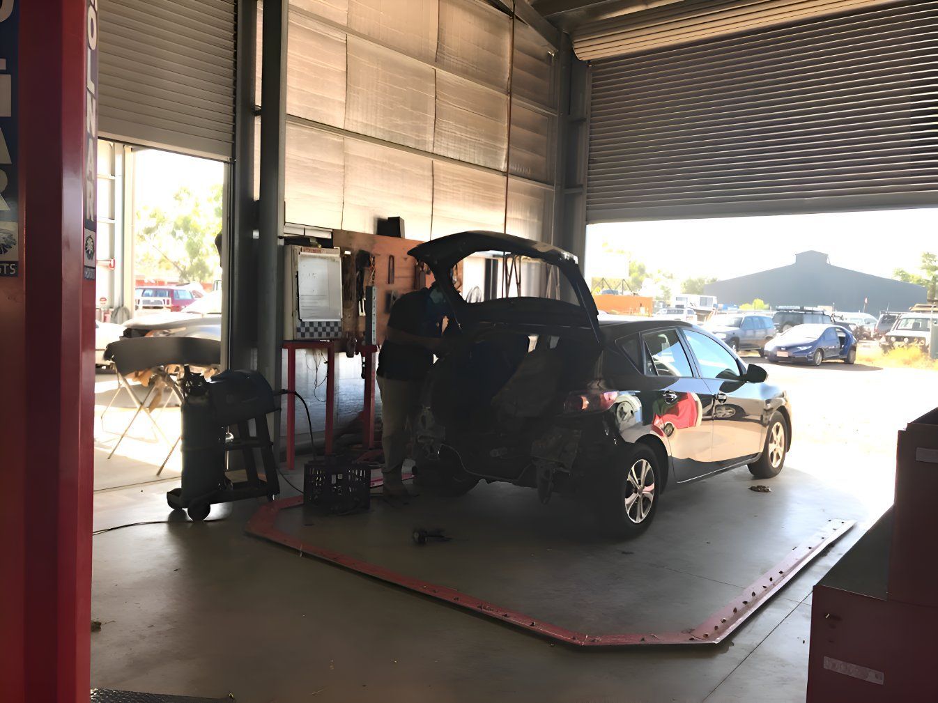 A Man Is Working On A Car In A Garage — P & V Panel Works In Alice Springs, NT