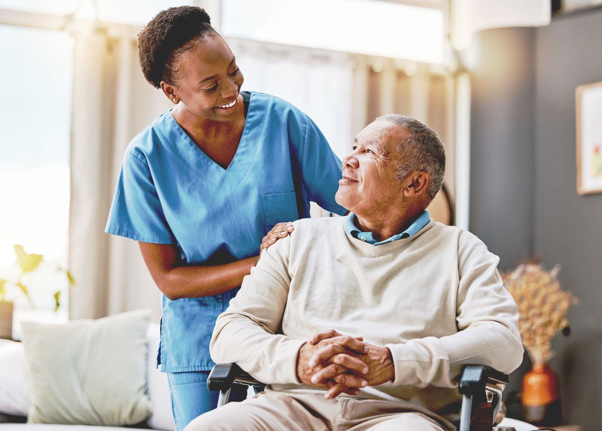 A nurse is standing next to an elderly man in a wheelchair.