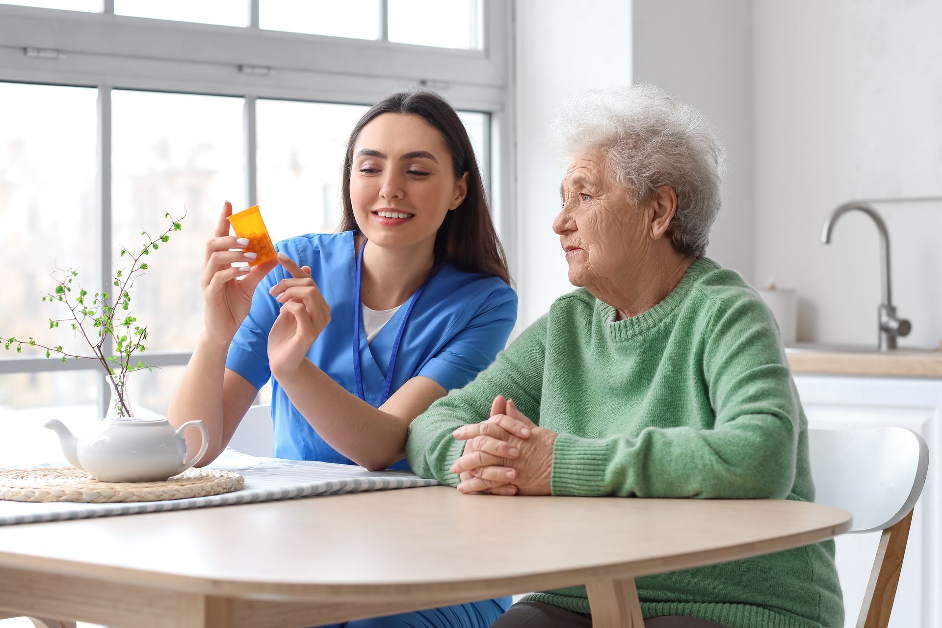 A nurse is giving an elderly woman a pill.