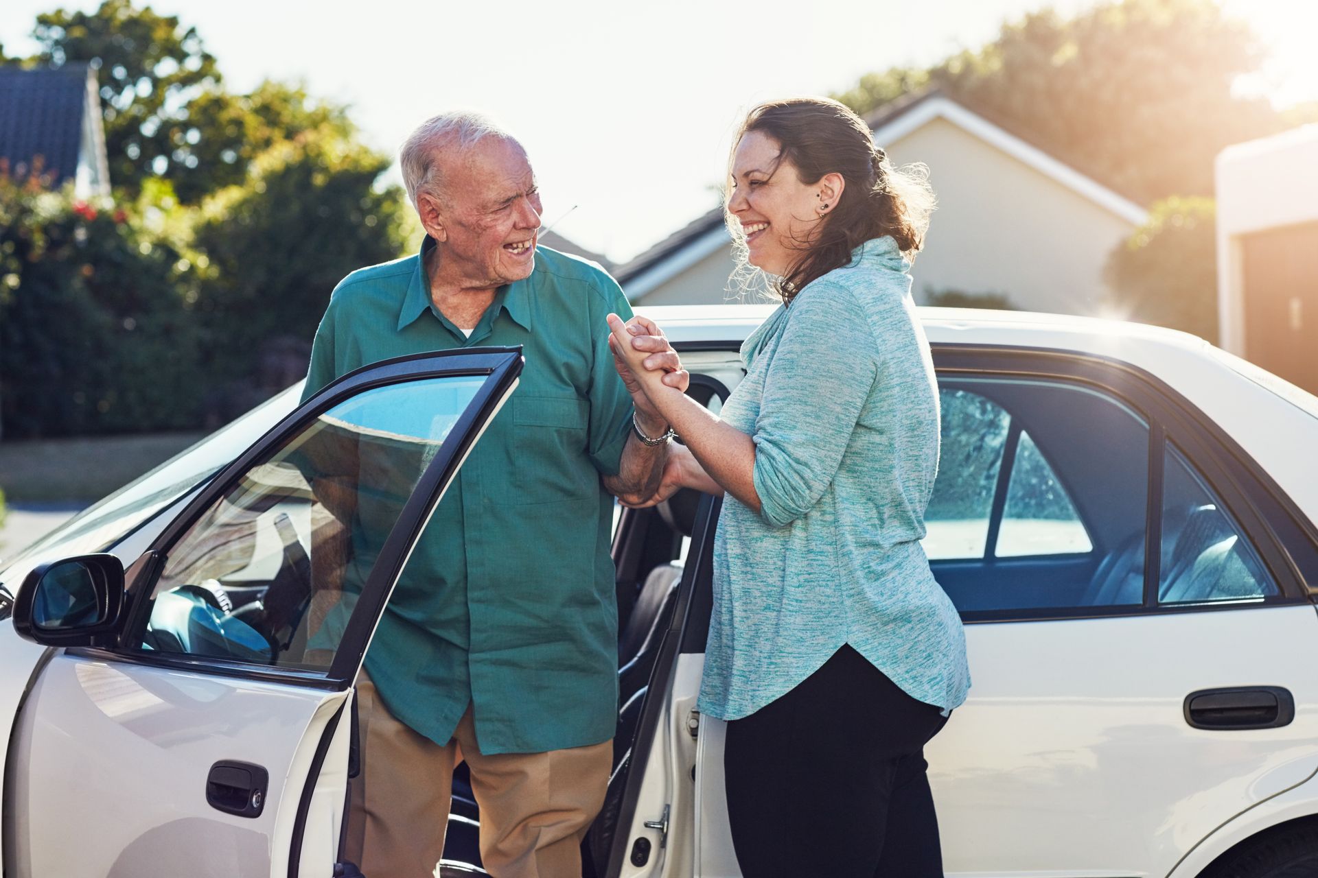 A woman is helping an older man get out of a car.