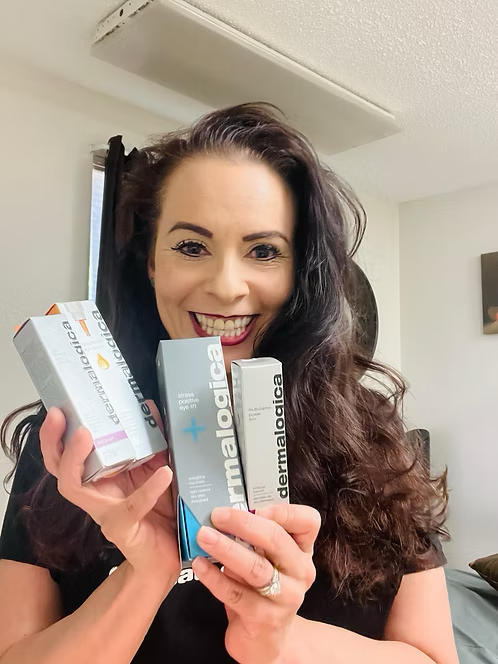 A woman is holding three boxes of dermalogica products in her hands.
