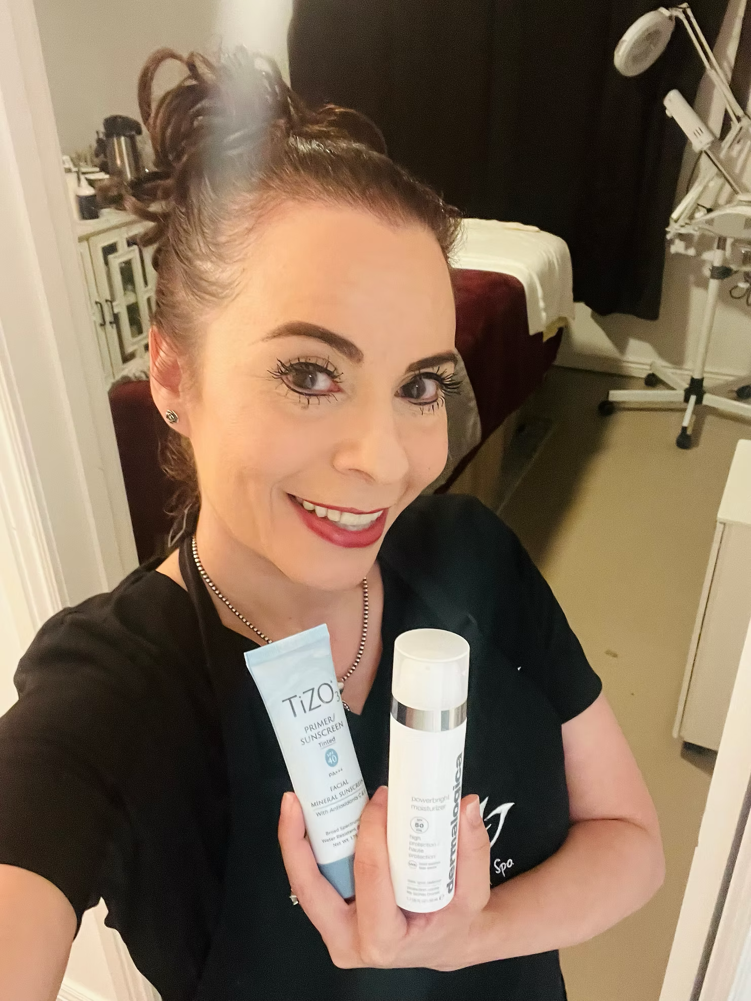 A woman in a black shirt is holding two bottles of lotion