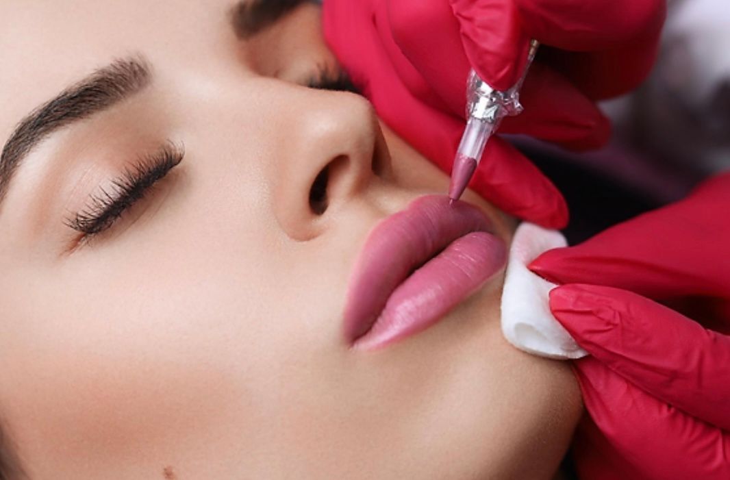 A woman is getting a permanent makeup tattoo on her lips.