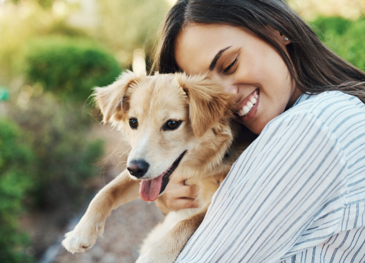 A woman is holding a small dog in her arms.
