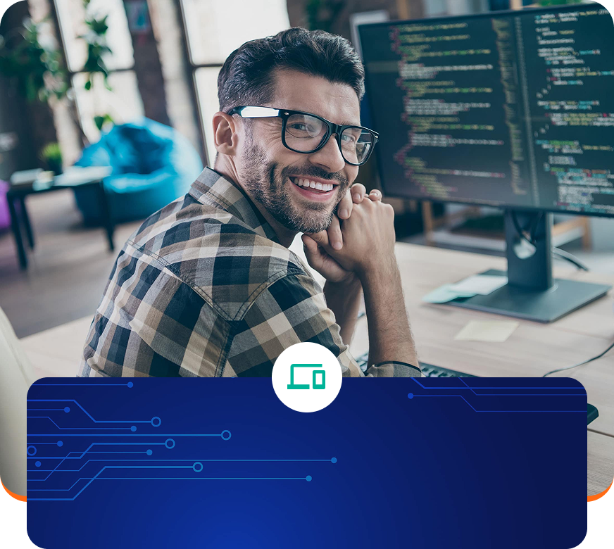 Smiling man at a desk with computer screens displaying code in a modern office