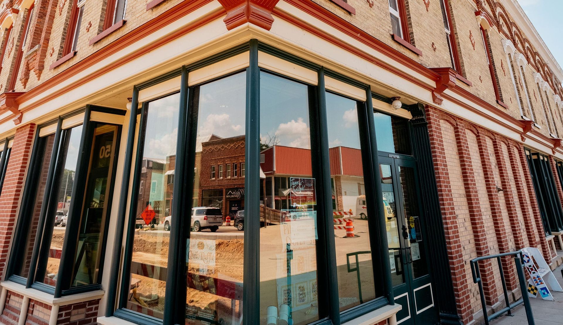 Corner storefront with large windows and striped brick facade on a city street