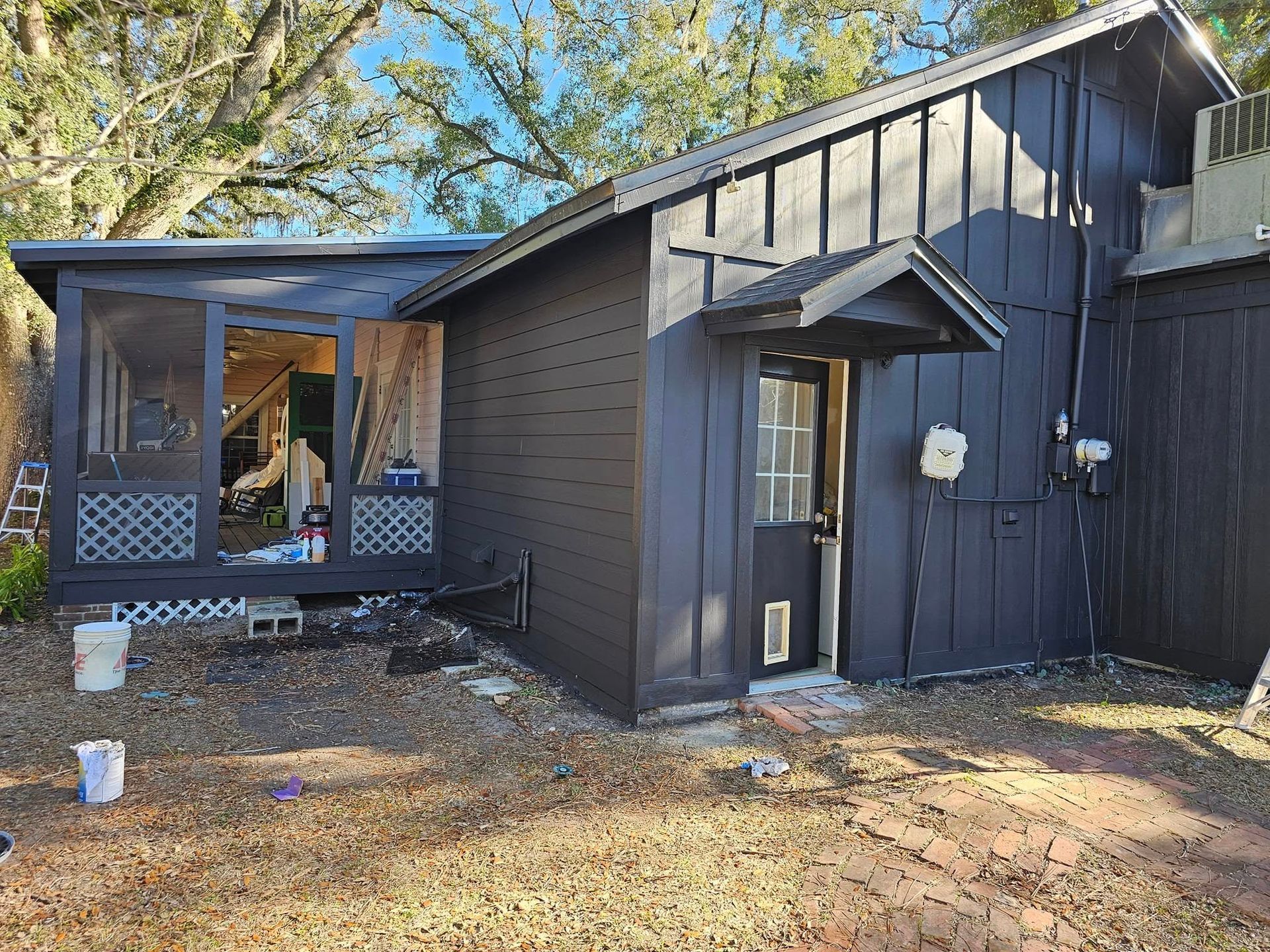 Black-painted shed with screened porch and doorway