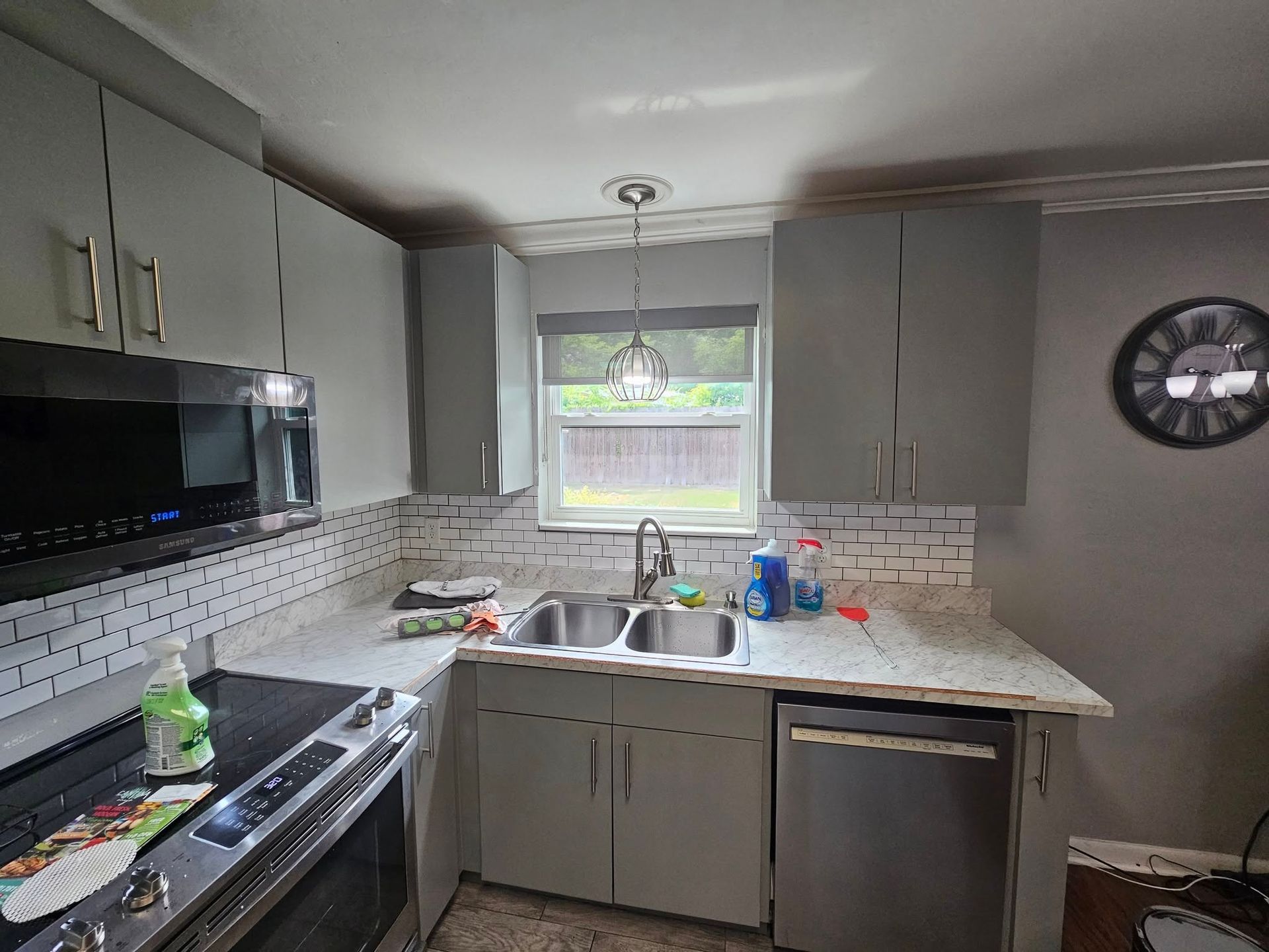 Gray kitchen with a sink under a window and stainless steel appliances