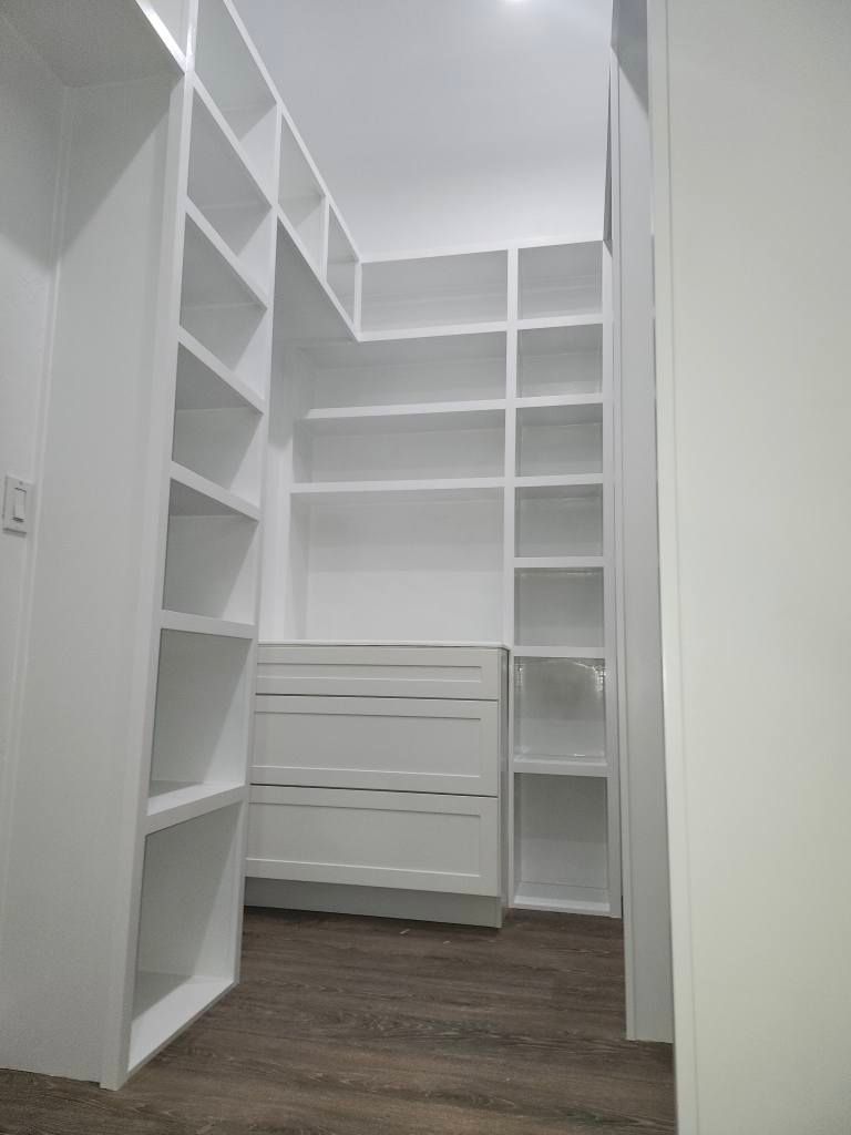 White walk-in closet with built-in shelving and drawers