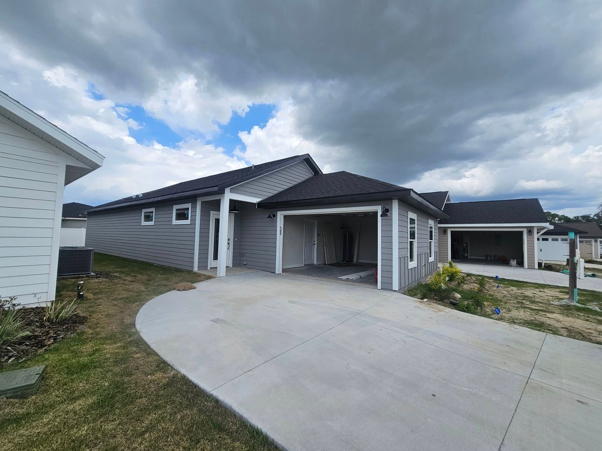 Gray house with a driveway under a cloudy sky