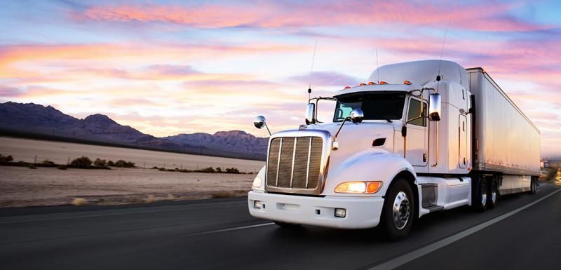 semi truck driving with sunset in background