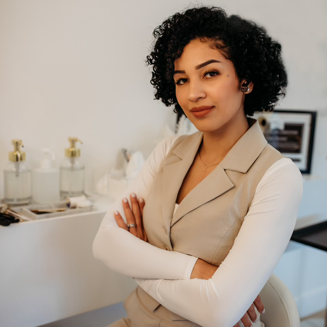 A woman with curly hair is sitting in a chair with her arms crossed