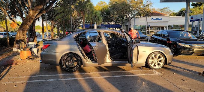 A silver car is parked in a parking lot with its doors open.