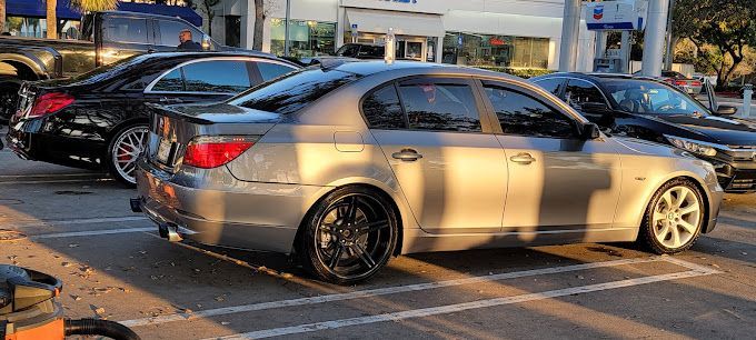 A silver car is parked in a parking lot next to a black car.