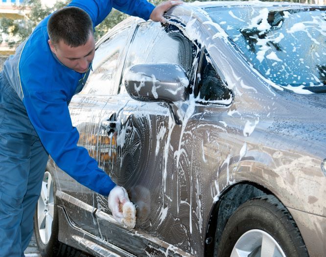 A man is washing a car with soap and water