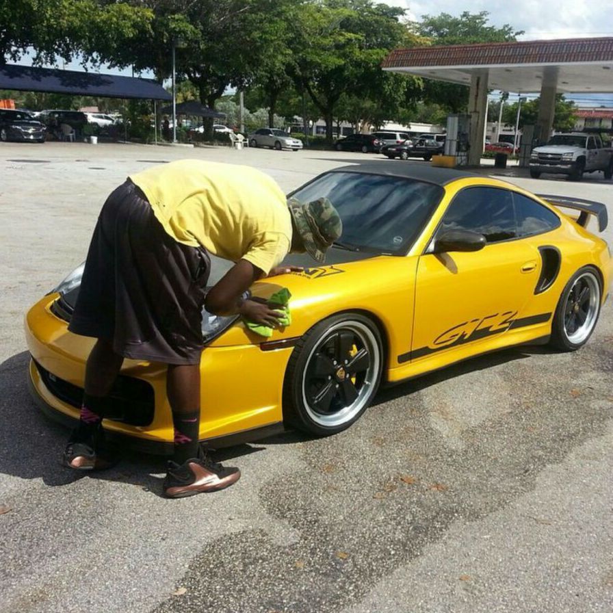 A man is cleaning a yellow porsche gt2