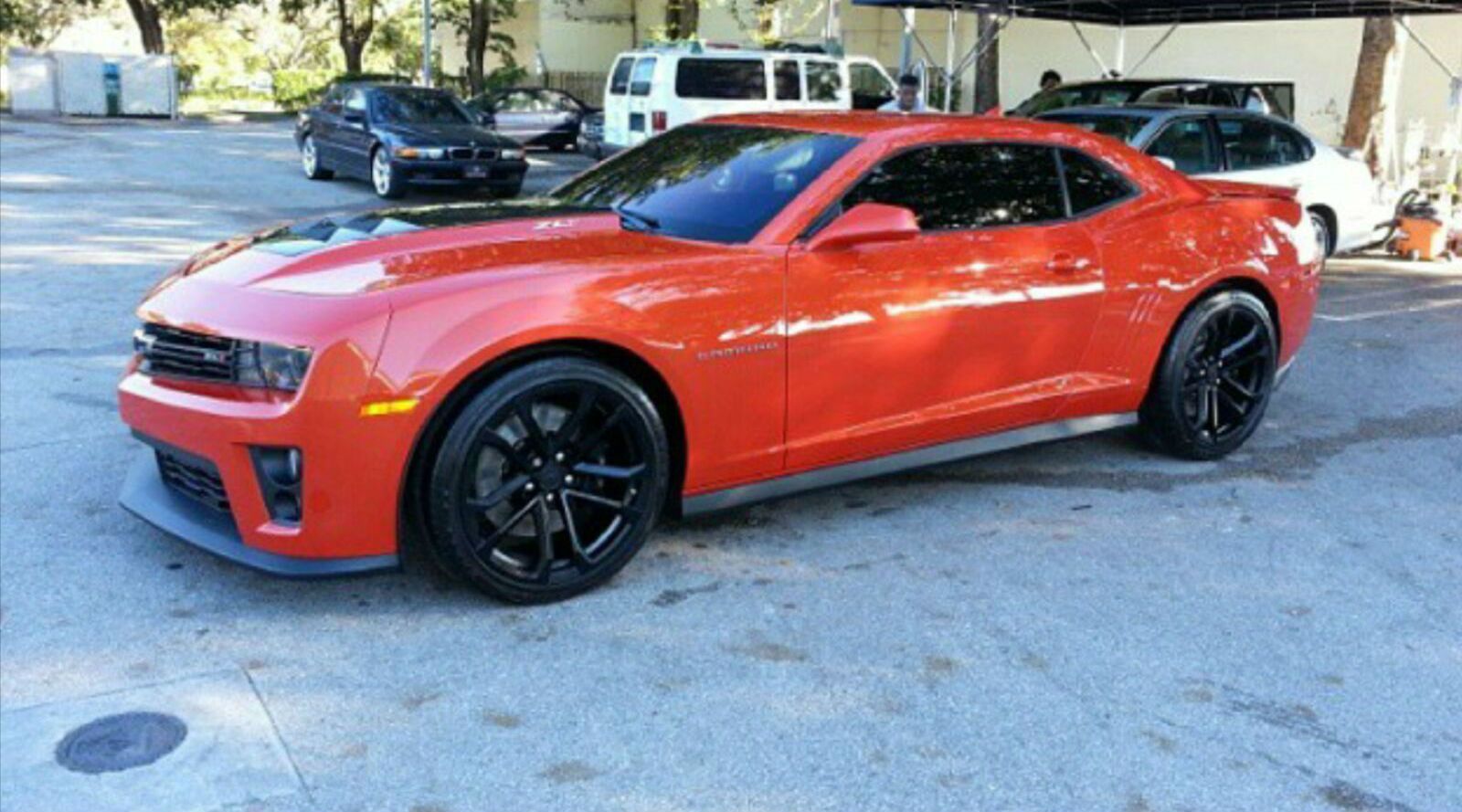 A red car with black wheels is parked in a parking lot.