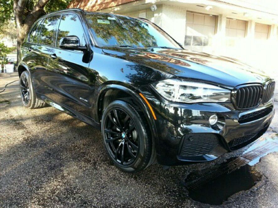 A black bmw x5 is parked in front of a house