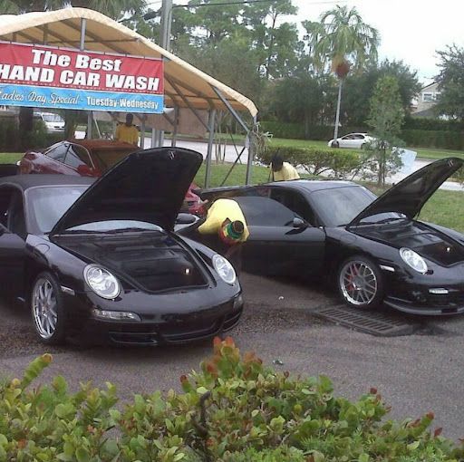 Two black sports cars are parked in front of a sign that says the best hand car wash