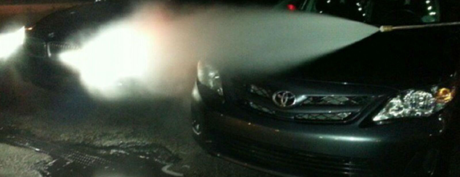 A car is being washed with a high pressure washer
