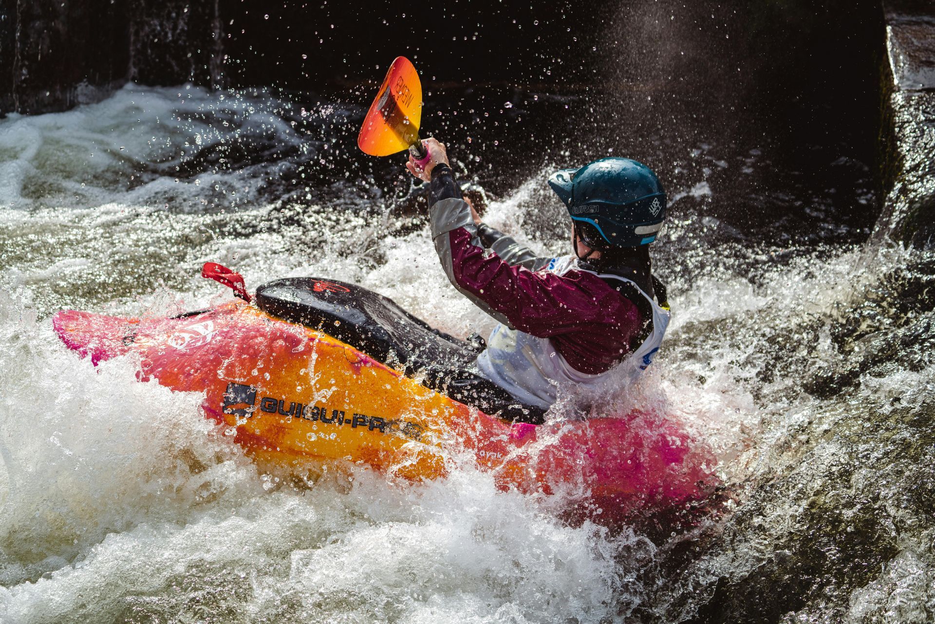 Kayaker in pink kayak paddling through splashing whitewater rapids with an orange paddle on the Ocoee river