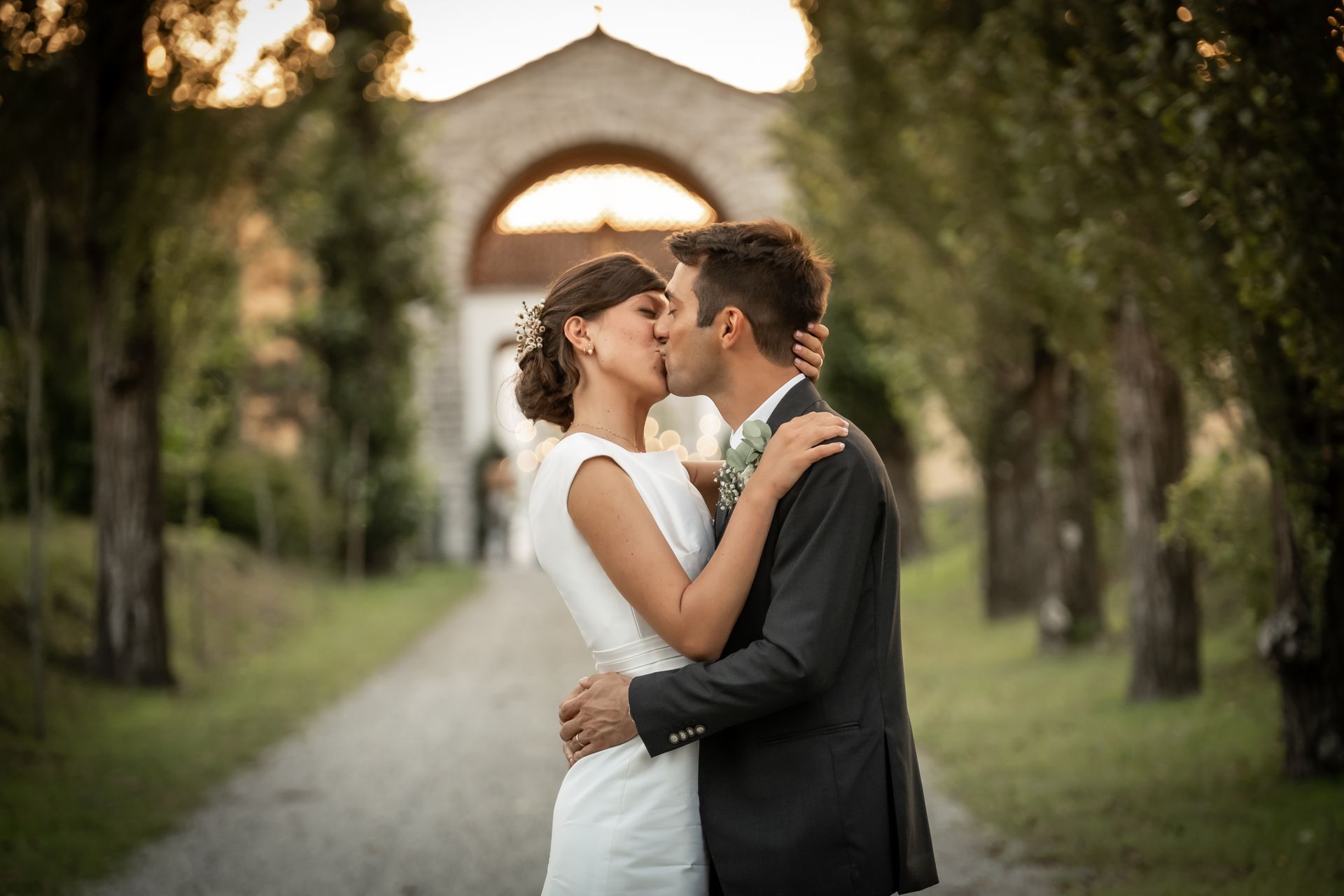 Coppia di sposi che si bacia su un sentiero alberato