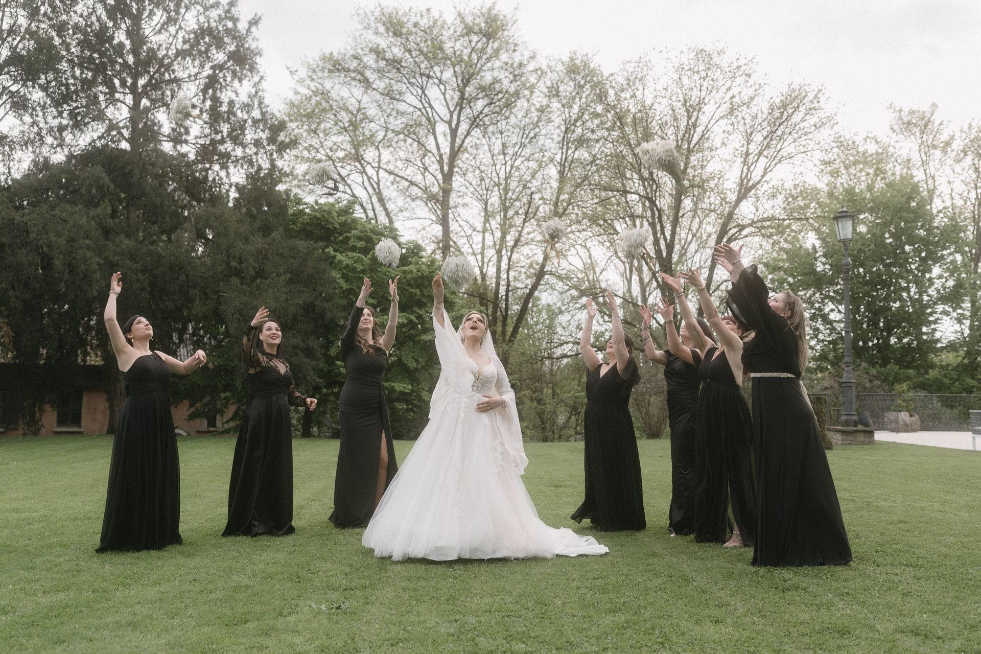 Sposa in abito su misura che lancia il bouquet alle damigelle 