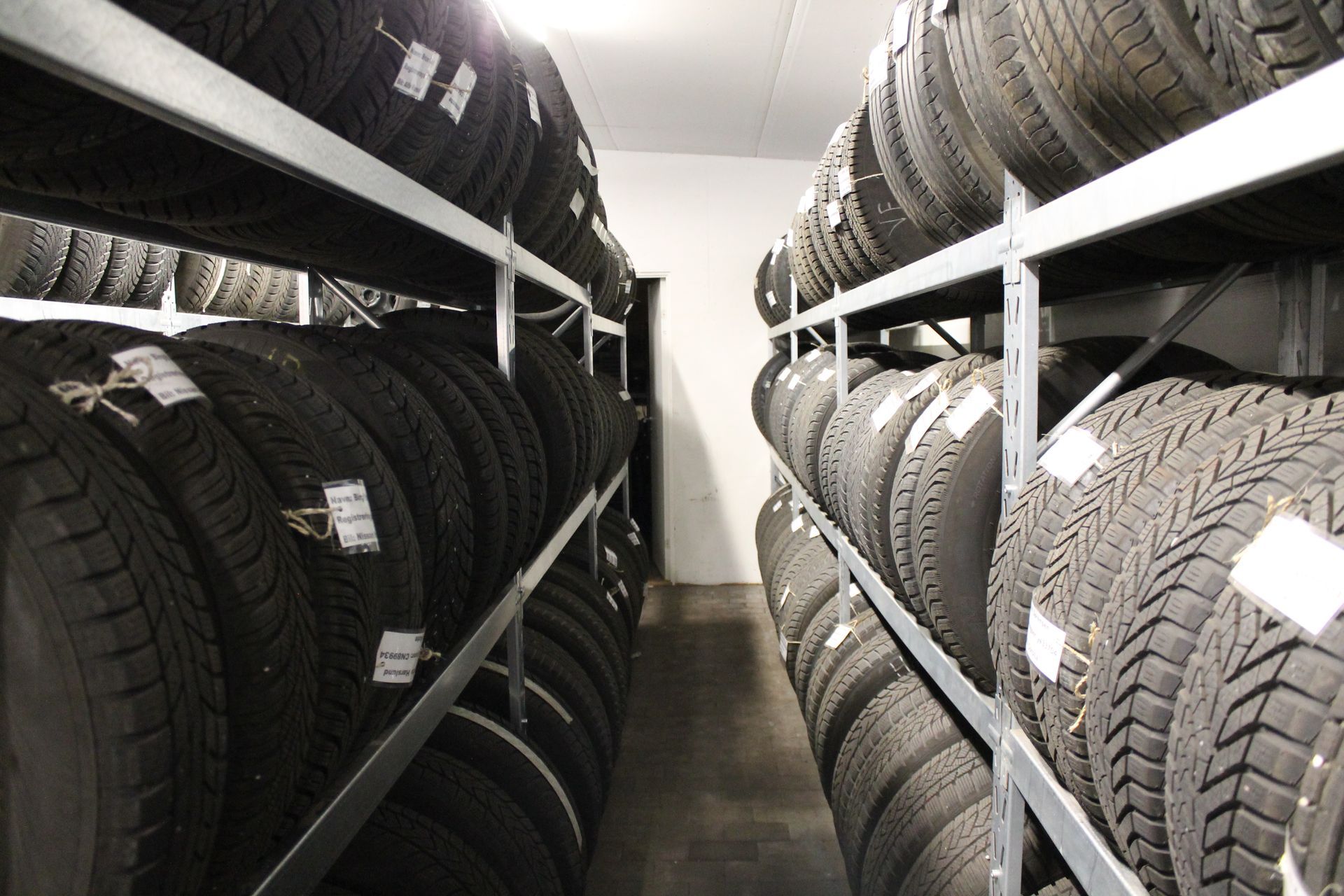 Dæk stablet på metalhylder inde i et opbevaringsrum.