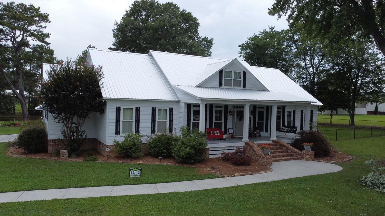 White house with black shutters and a metal roof