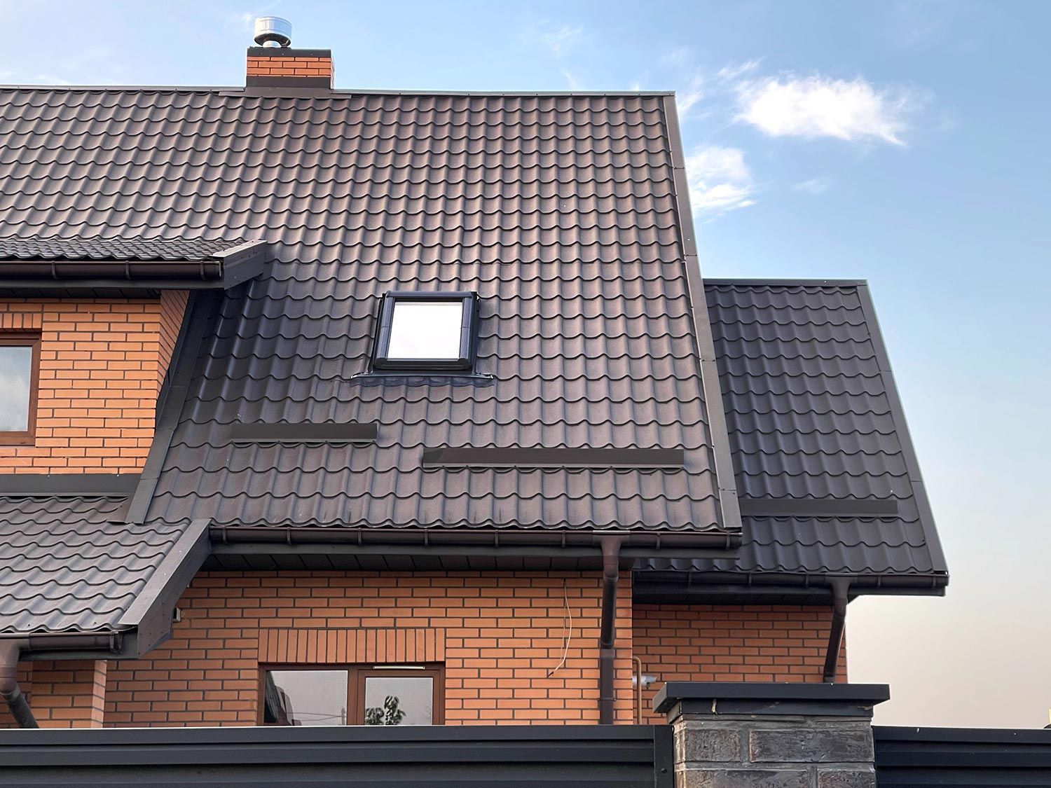 Brick house with a dark brown metal tile roof