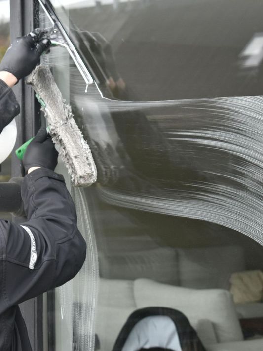 Close up of man cleaning dirty window with cleaning equipment