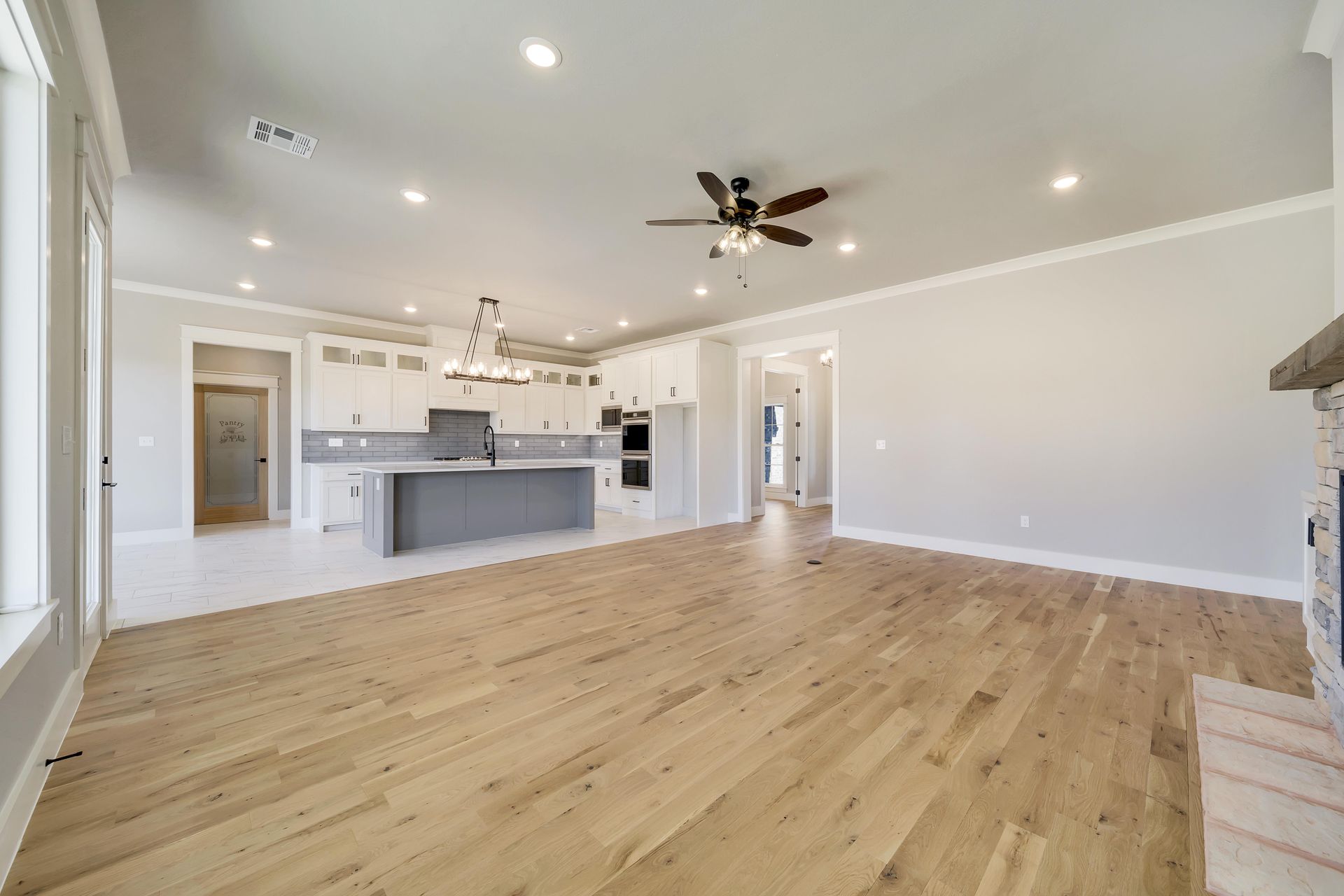 Woman in straw hat smiles, holding wine glass near a lake.