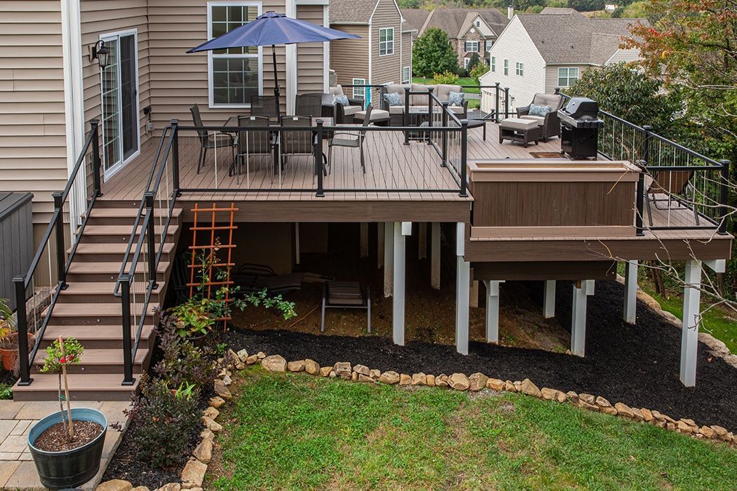 A large deck with a table and chairs and a blue umbrella