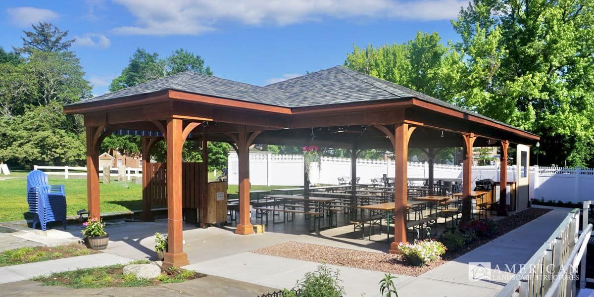 A large wooden gazebo with tables and chairs underneath it