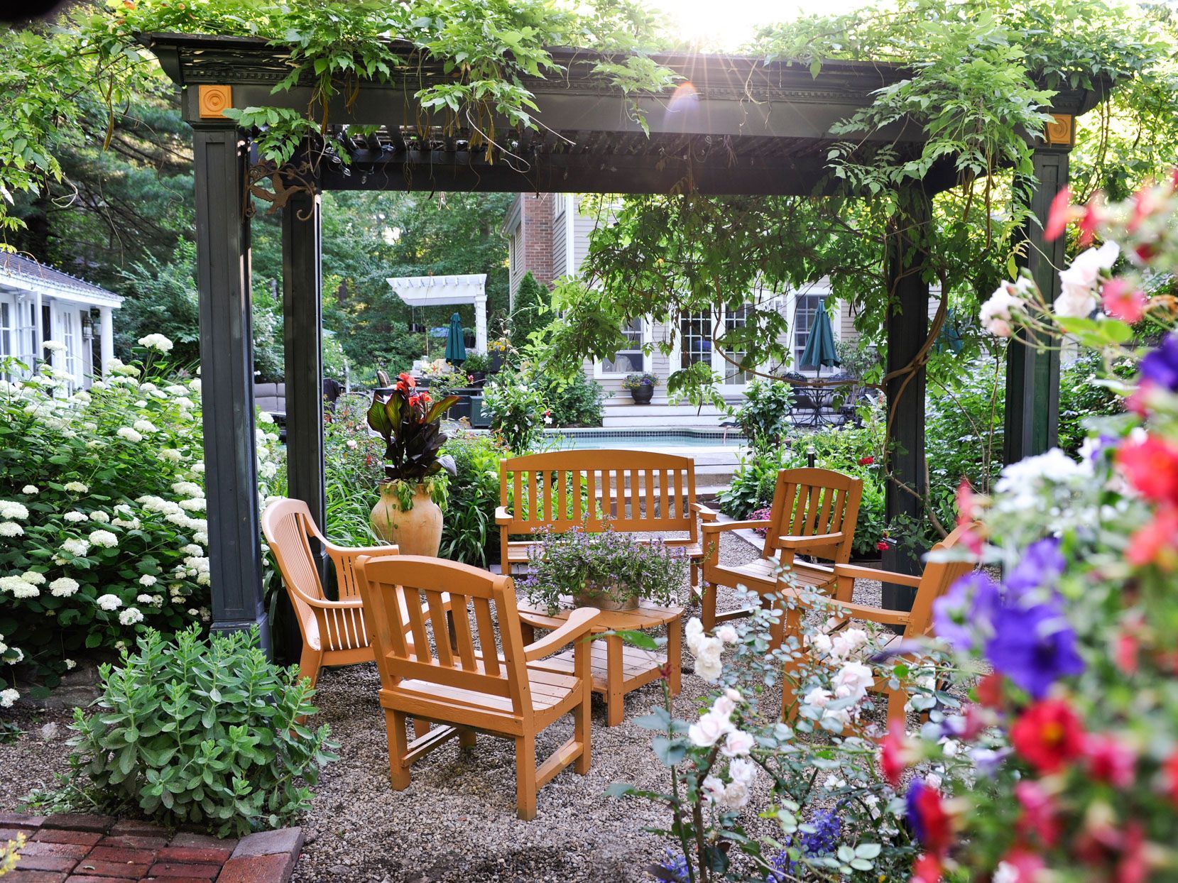 A pergola with a bench and chairs underneath it